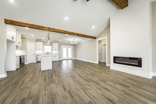 unfurnished living room with dark wood finished floors, a glass covered fireplace, beamed ceiling, and a sink