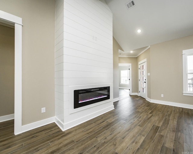 unfurnished living room with baseboards, dark wood finished floors, visible vents, and a healthy amount of sunlight