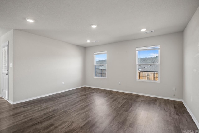 spare room with dark wood-style flooring, recessed lighting, visible vents, and baseboards