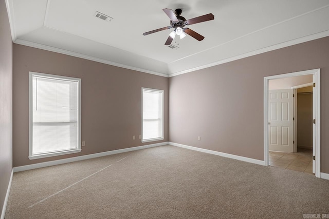 empty room with light carpet, a ceiling fan, baseboards, a tray ceiling, and crown molding