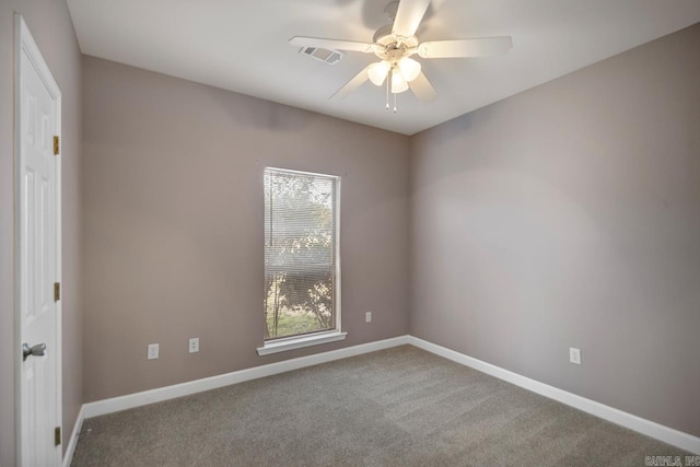 empty room with carpet flooring, visible vents, ceiling fan, and baseboards