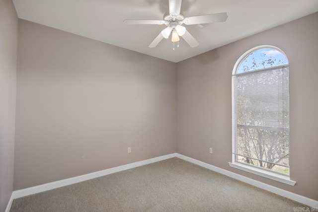 carpeted spare room with ceiling fan and baseboards