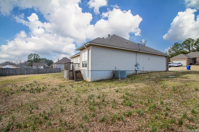 view of property exterior featuring central AC unit, fence, a deck, and a yard