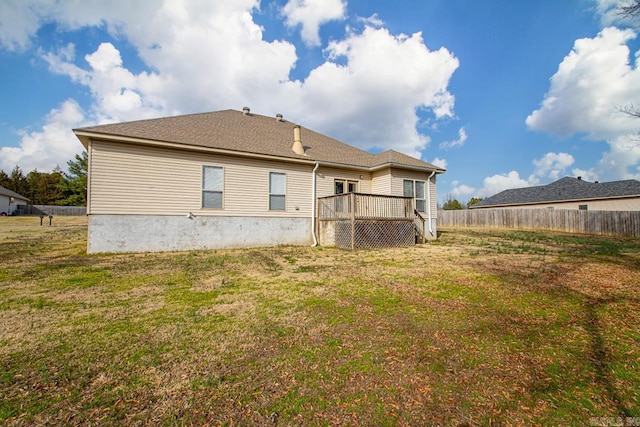 rear view of house featuring a deck, a yard, and fence
