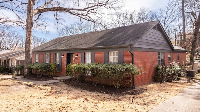 ranch-style house with brick siding, roof with shingles, and cooling unit