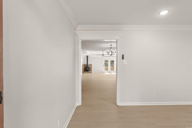 hall with ornamental molding, an inviting chandelier, wood finished floors, and baseboards