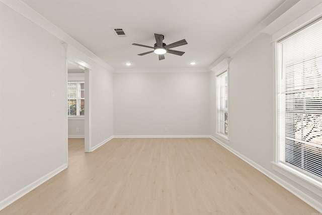 spare room featuring light wood-style floors, baseboards, visible vents, and crown molding