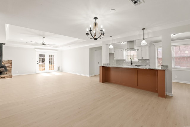 kitchen with backsplash, a raised ceiling, visible vents, and range hood