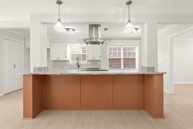 kitchen with decorative backsplash, a peninsula, island exhaust hood, white cabinetry, and a sink