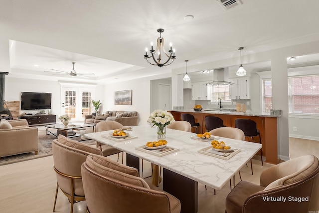 dining space featuring a tray ceiling, visible vents, and plenty of natural light