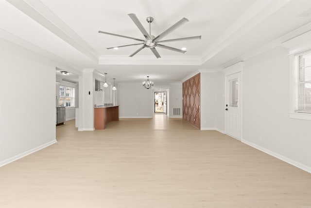 unfurnished living room featuring a tray ceiling, visible vents, a chandelier, light wood-type flooring, and baseboards