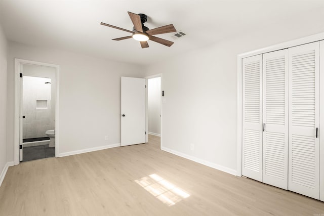 unfurnished bedroom featuring a closet, connected bathroom, light wood-style flooring, and baseboards