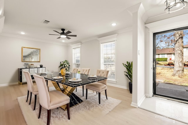 dining space with light wood finished floors, baseboards, visible vents, and crown molding