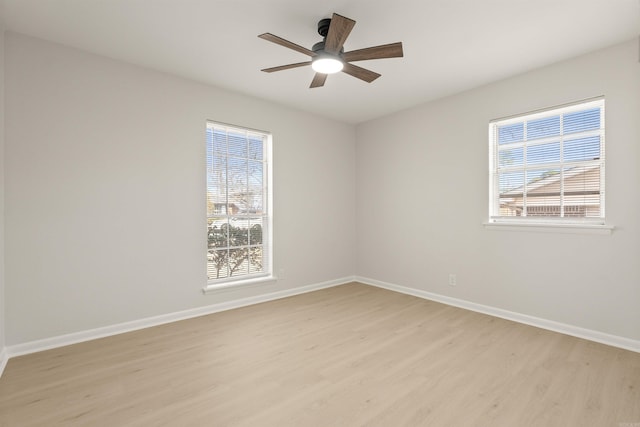 spare room featuring light wood-style floors, plenty of natural light, baseboards, and ceiling fan