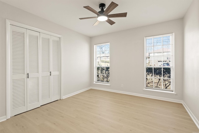 unfurnished bedroom with light wood-style floors, a closet, baseboards, and a ceiling fan