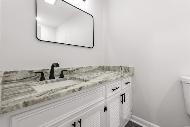 bathroom with toilet, baseboards, and vanity