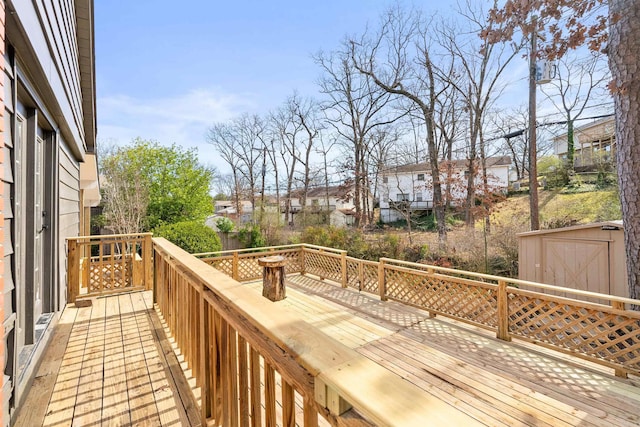 wooden terrace featuring an outbuilding, a storage unit, and a residential view