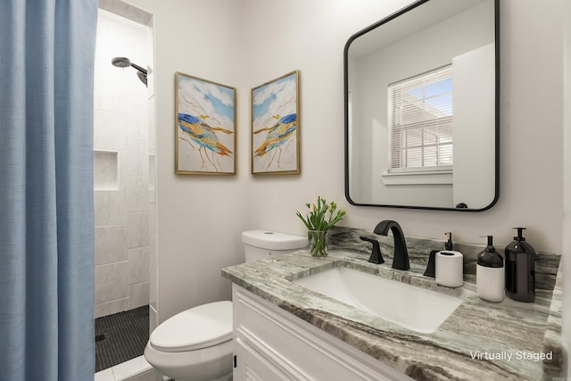 full bathroom featuring vanity, a tile shower, and toilet