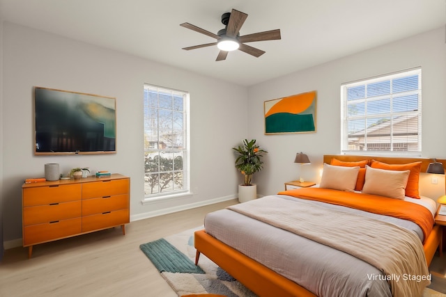 bedroom featuring light wood-style floors, multiple windows, ceiling fan, and baseboards