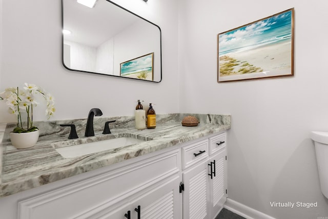 bathroom featuring toilet, baseboards, and vanity