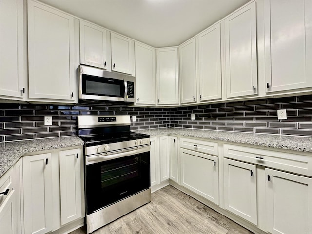 kitchen featuring stainless steel appliances, tasteful backsplash, light wood-type flooring, and white cabinets