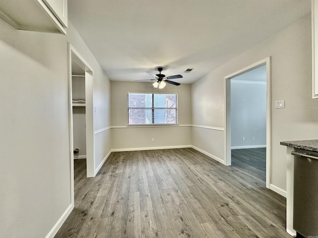 interior space with baseboards, ceiling fan, visible vents, and wood finished floors