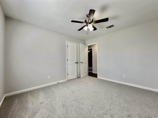 empty room featuring a ceiling fan, carpet, visible vents, and baseboards