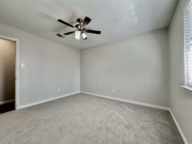 carpeted spare room featuring a ceiling fan, visible vents, and baseboards