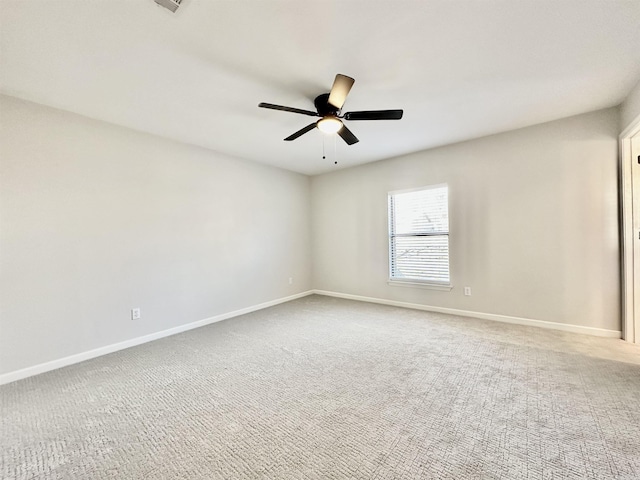 carpeted spare room featuring a ceiling fan and baseboards