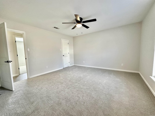 carpeted spare room with visible vents, ceiling fan, and baseboards