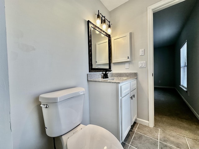 bathroom with toilet, tile patterned floors, baseboards, and vanity