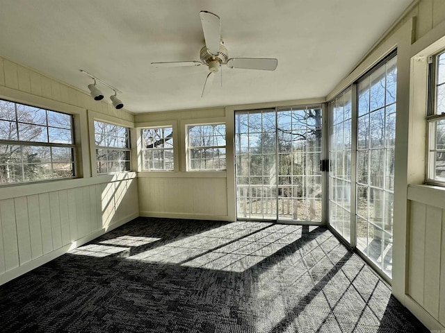 unfurnished sunroom with ceiling fan, track lighting, and a wealth of natural light