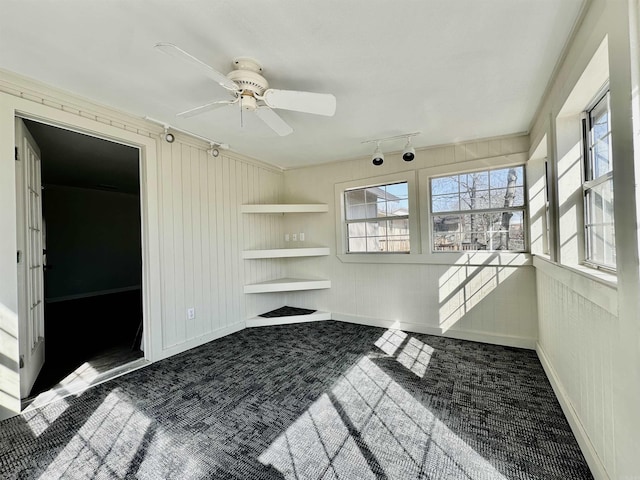 unfurnished room with carpet floors, track lighting, baseboards, and a ceiling fan