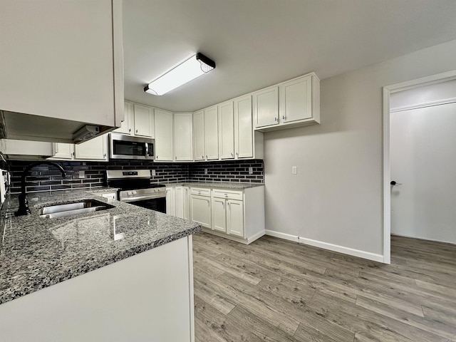 kitchen featuring stone countertops, white cabinets, decorative backsplash, appliances with stainless steel finishes, and a sink