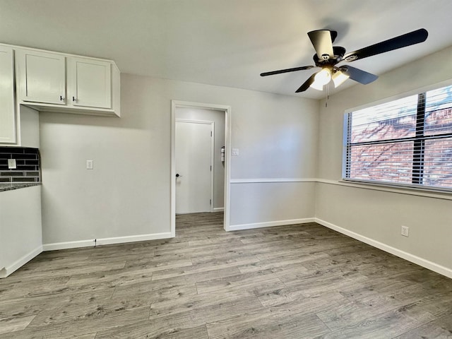 interior space featuring light wood finished floors, a ceiling fan, and baseboards