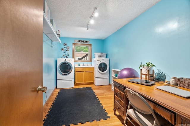 laundry area featuring cabinet space, light wood-style floors, a sink, a textured ceiling, and washer and dryer