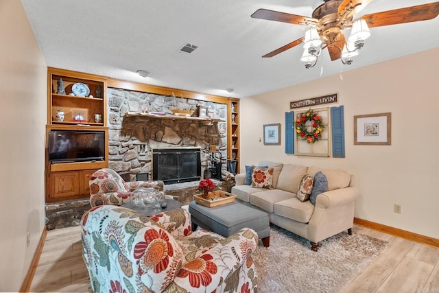 living area with light wood finished floors, baseboards, a fireplace, and visible vents