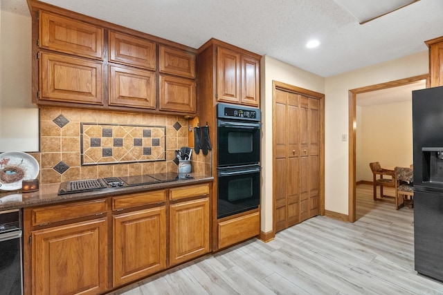 kitchen with black appliances, tasteful backsplash, brown cabinetry, and light wood-type flooring