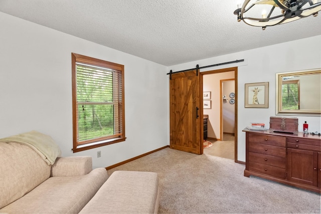 living area with light carpet, a barn door, baseboards, and a textured ceiling