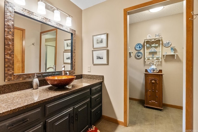 full bath featuring tile patterned flooring, a shower with door, vanity, and baseboards