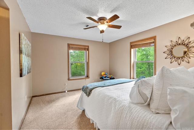 carpeted bedroom with multiple windows, ceiling fan, a textured ceiling, and baseboards