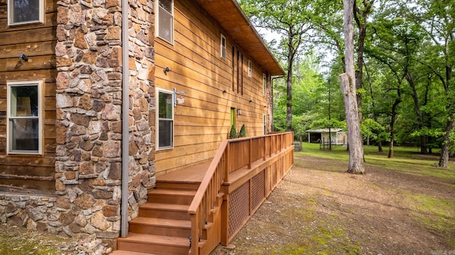 view of side of home with stone siding and a wooden deck