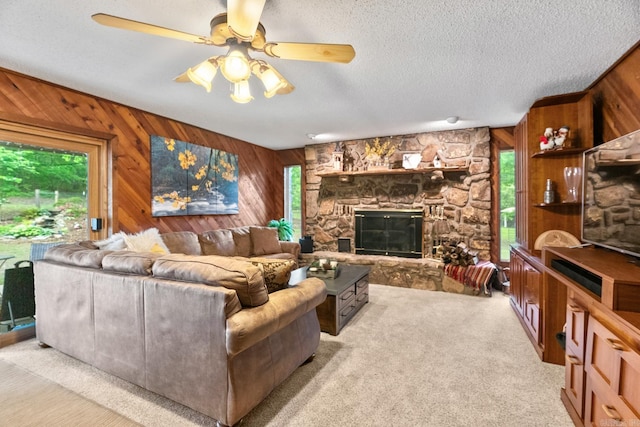 carpeted living room with a fireplace, wooden walls, a textured ceiling, and ceiling fan