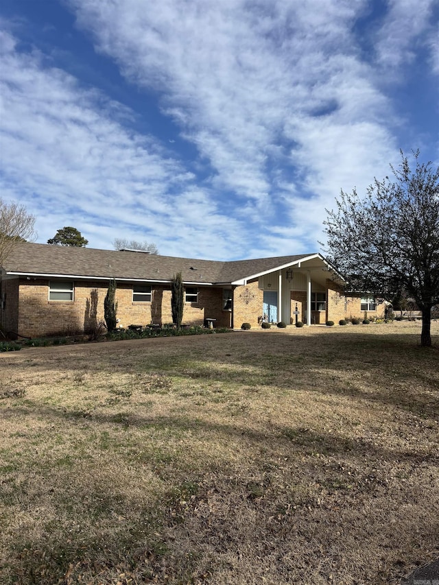 back of house featuring brick siding and a yard