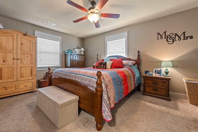 bedroom featuring a textured ceiling, carpet flooring, visible vents, and a ceiling fan