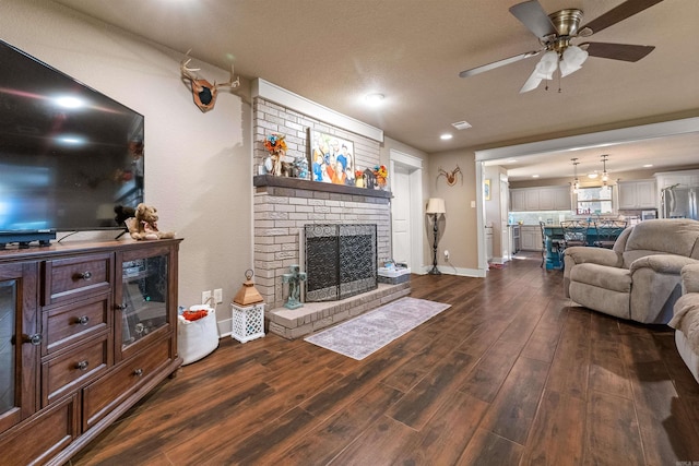 living area with visible vents, a brick fireplace, ceiling fan, wood finished floors, and baseboards