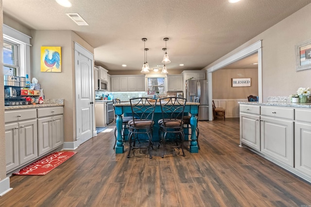 dining space with dark wood-type flooring, visible vents, plenty of natural light, and a textured ceiling