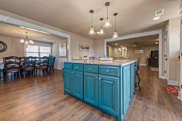 kitchen featuring a center island, pendant lighting, dark wood finished floors, blue cabinetry, and visible vents