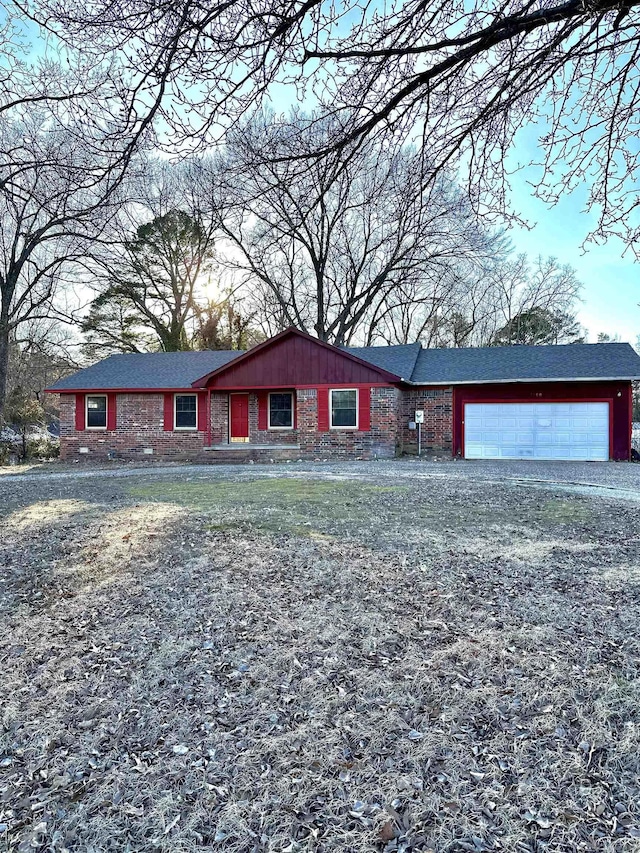 ranch-style home with a garage, gravel driveway, and brick siding