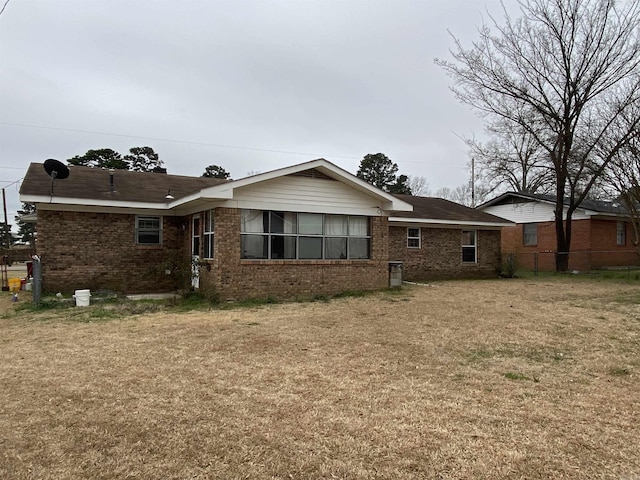 back of house featuring a yard, fence, and brick siding